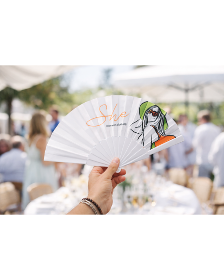 View of a personalized fan being used at a wedding